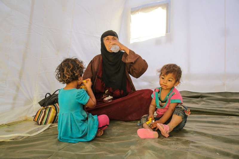 تجلس هذه السيدة العراقية مع ولديها في خيمة بالقرب من نقطة تفتيش في الخضير بالقرب من أربيل. بعد هروبهم من الموصل، مشوا طيلة أربعة أيام. ليس لديهم المال أو أي مكان يذهبون إليه. توفر لهم حكومة إقليم كردستان والمفوضية المأوى، ولوازم النظافة والإمدادات الأساسية الأخرى. 