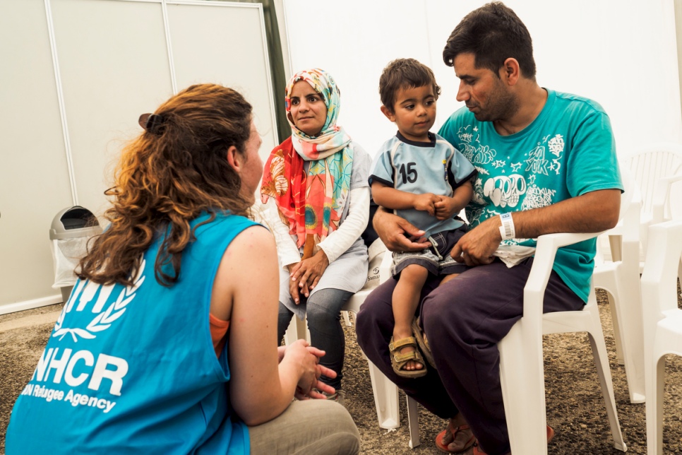 Ghulam Ali Jaffari, his wife Nabila, and their two-year-old son Amir talk with UNHCR staff while waiting to collect their newly issued ID's by the Greek Asylum Service.