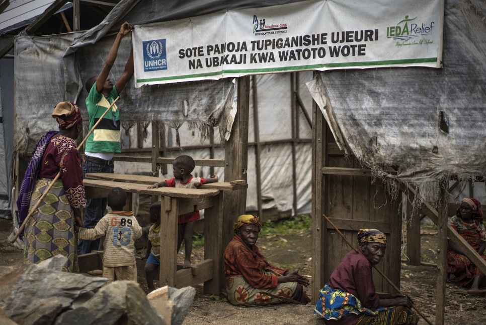 Mustafa, a psychologist with UNHCR partner IEDA, adjusts a banner about sexual violence in Kilimani IDP camp, Masisi, Democratic Republic of the Congo.