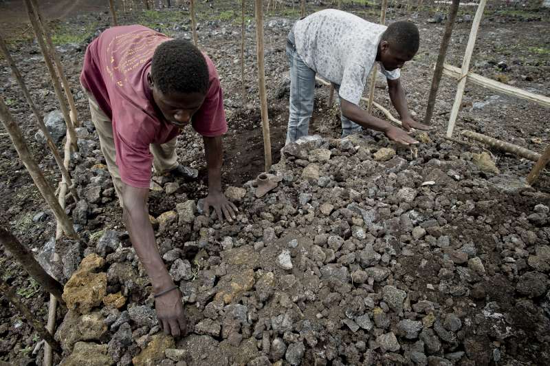 Baseme and his brother-in-law create the floor of their shelter from volcanic rock. The whole family will sleep on this.