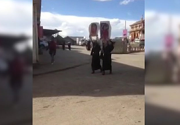 Two Tibetan women in Ngaba carry photos of the Dalai Lama in a public protest, Nov. 16, 2016.