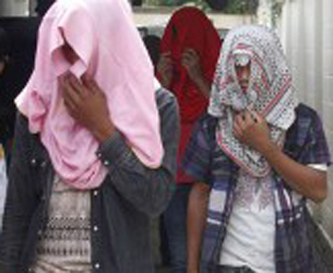 Lao workers, who were held in cages on a pig farm in central Thailand's Nakhon Pathom province, hide their faces as they head to a state-run shelter, Aug. 23, 2015.