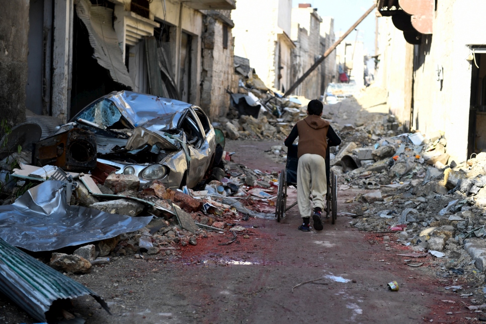 Un garçon pousse une chaise roulante à travers les décombres du quartier d'Al-Mashatiyeh, à Alep-Est.