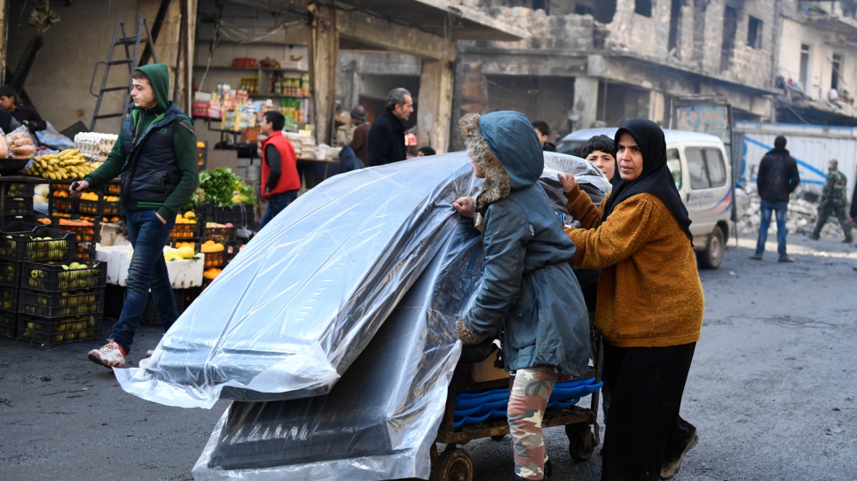 A woman and her two children push a cart carrying relief items distributed by UNHCR and other UN partners in the Tariq Al-Bab neighborhood in eastern Aleppo.  