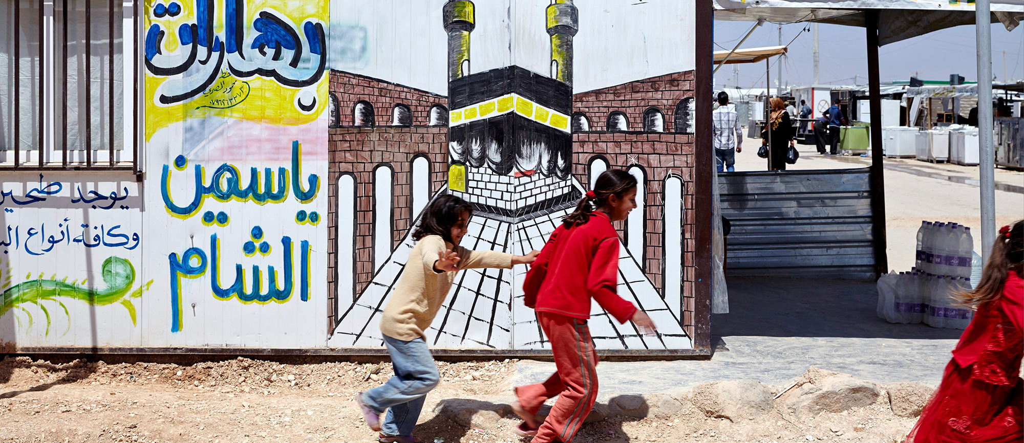 Photo of a caravan and two young refugees in Za'atari camp.