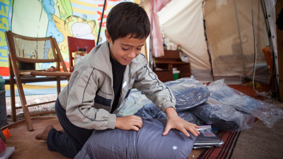 An Afghan boy opens a winter kit that will help him face harsh weather conditions at the open accommodation site of Agios Andreas in Attica, Greece.