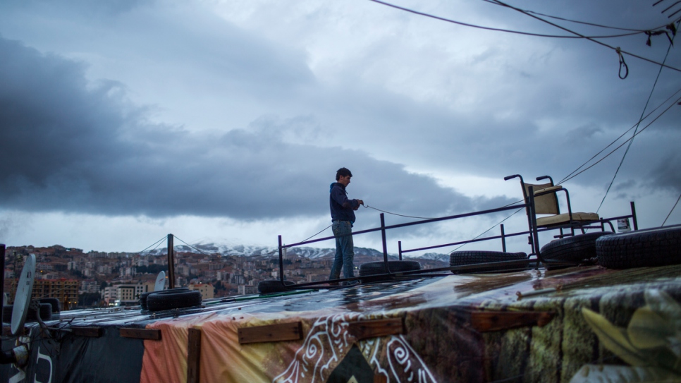 A young Syrian refugee tries to fix the wiring on top of a shelter at an informal settlement in the Bekaa Valley, Lebanon.