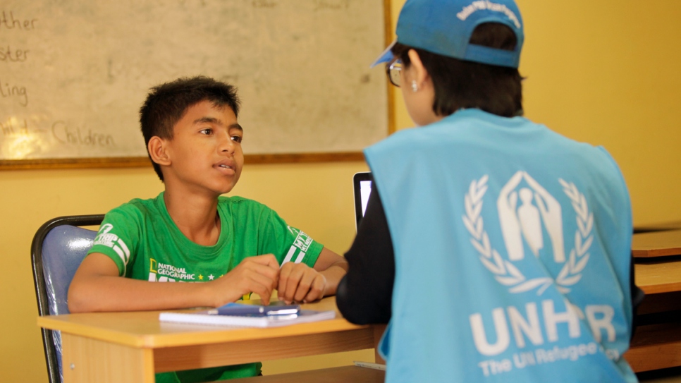 Yasin, a 10-year-old Rohingya refugee, speaks with a UNHCR staff member in Indonesia.
