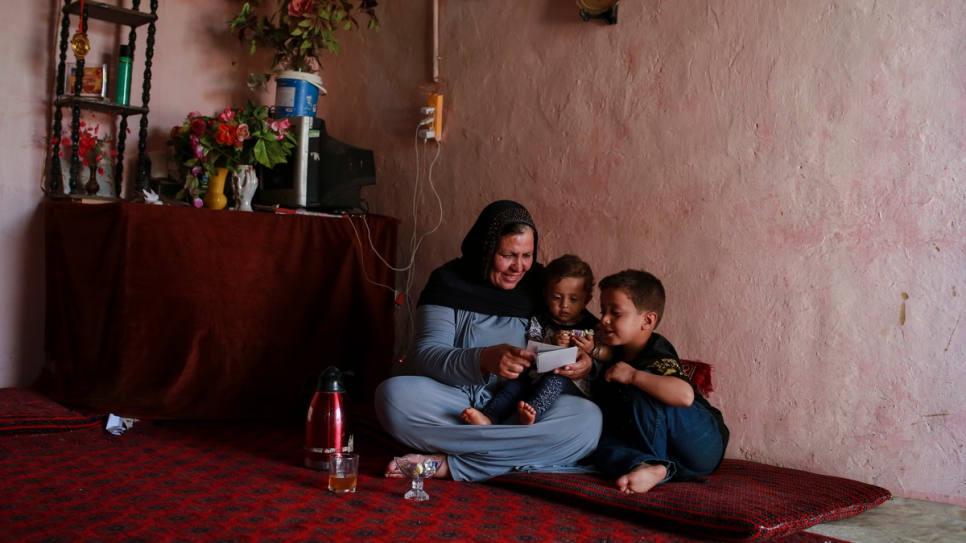 Aqeela montre des photos de sa jeunesse en Afghanistan à ses petits-enfants, dans sa maison au village de réfugiés de Kot Chandana. 