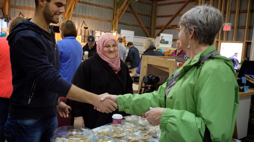 Rabiaa et son fils, Majd, saluent un client au marché local du week-end. 