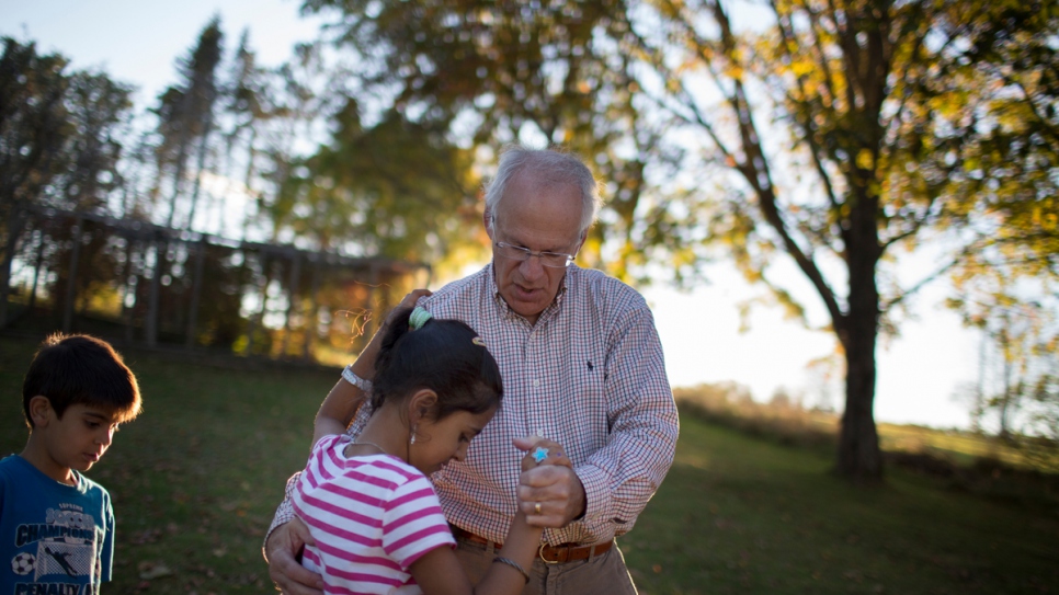 David Friendly, leader of a private sponsorship group, plays with the Ayash children at their home in Lunenburg.