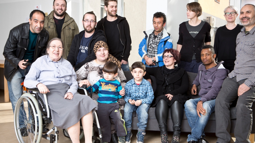 Clients and co-workers surround Frau Bock in her wheelchair in a communal space at Ute Bock Haus.