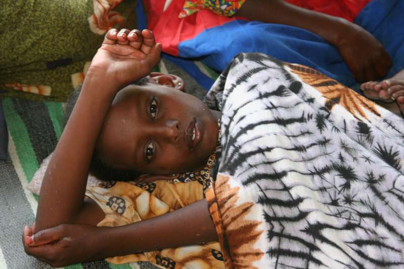 A young Somali girl who survived eight days adrift at sea in a smuggler's boat recuperates on the floor of a large tent in Bossaso.