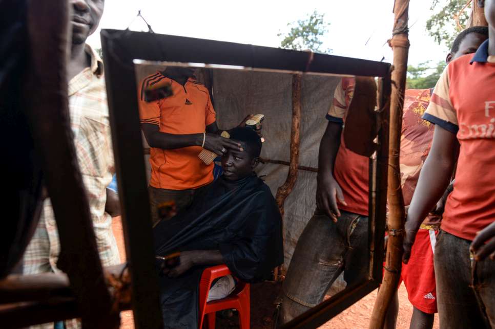 A young refugee gets his hair cut at one of the few shops in the camp market.