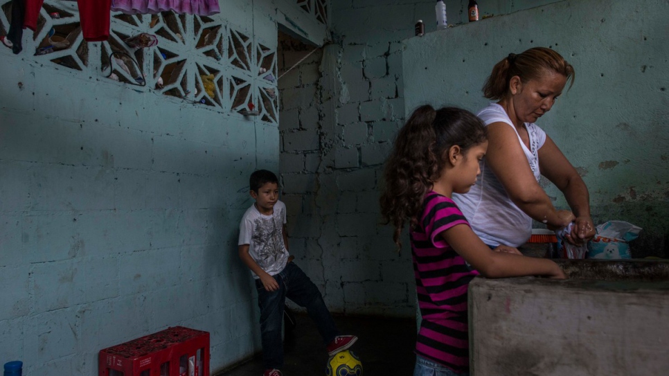 Brenda washes clothes with her children. The years of abuse that Brenda suffered at the hands of her partner nearly tore her family apart.