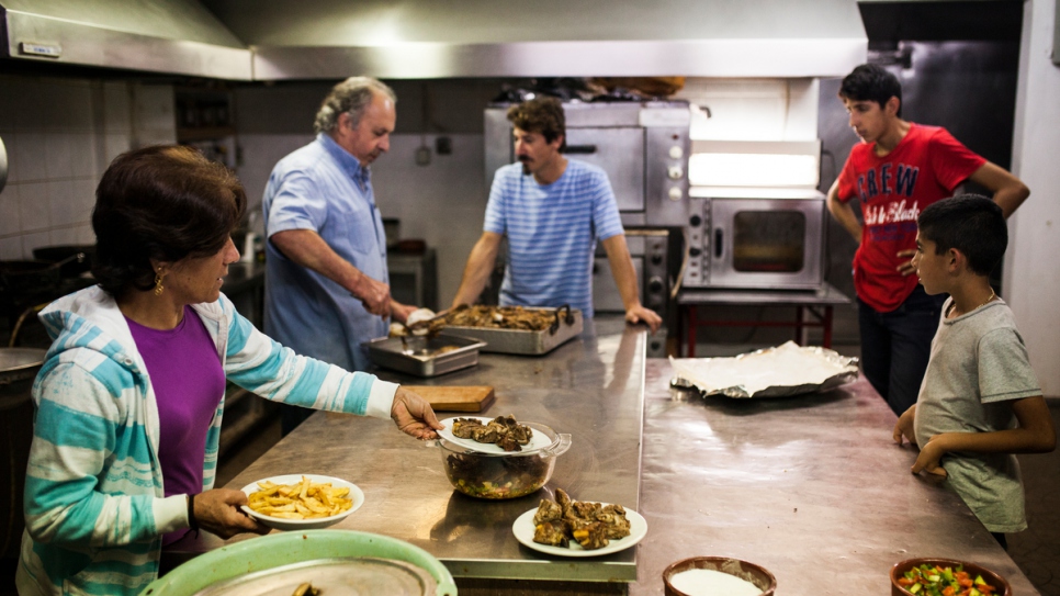 Syrian refugees and Solidarity Now staff prepare lunch in the hotel's communal kitchen.