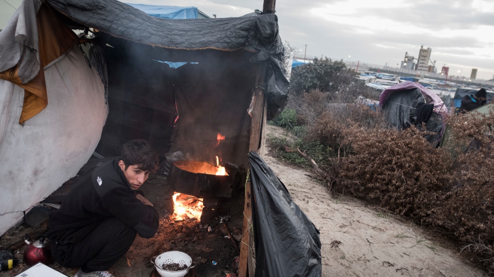 A young Afghan refugee prepares dinner in a makeshift kitchen in Calais, France, October 12, 2016.