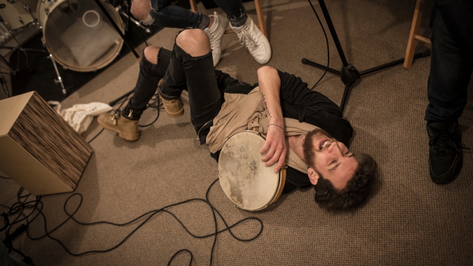 Syrian drummer Ali Hasan lies on the floor laughing during Musiqana's band practice at the Super Sessions cafe in Berlin.
