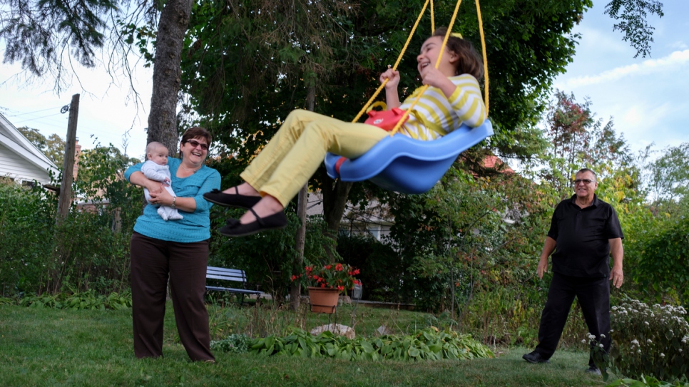 Les bénévoles Tanna et Joe jouent avec Bayan et Adam, âgé de six mois, dans leur jardin. 