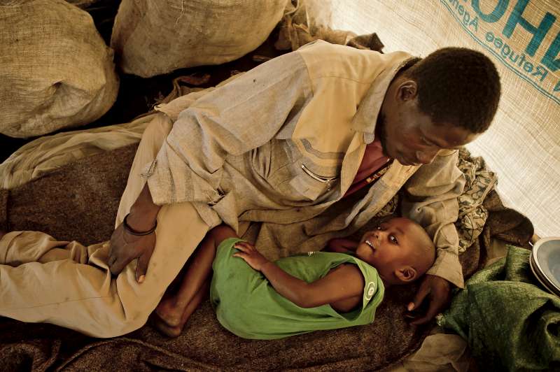 Le père de Sukuru, Basémé. On le voit ici avec l'un de ses cadets dans la tente commune où la famille a trouvé abri à son arrivée à Mugunga III. La famille s'est installée depuis dans une case bien plus spacieuse.