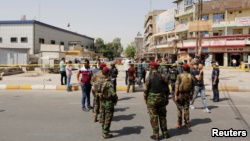 Iraqi security forces gather at the site of a suicide bomb blast in Baghdad al-Jadida on September 27.