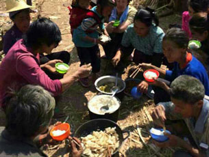 Ethnic Kokang refugees eat a meal of beans and pickled vegetables in the open air. Feb. 27, 2015