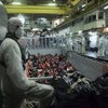 Militares del San Giorgio esperan para procesar a los recién rescatados, mientras el GIS atraca en la bodega del barco.