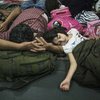 Una pequeña niña siria que viajó con su mochila escolar, duerme sobre el brazo de su padre.  Juntos escaparon de la inseguridad en su país y han viajado cientos de kilómetros.