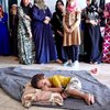 Un pequeño niño duerme sobre una manta con su cabeza en una almohada acompañado por las mujeres y niñas de su numerosa familia ampliada, que huyó de sus hogares en Mosul.