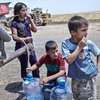 Niños iraquíes provenientes de Mosul llenan bidones de agua en un camión aljibe en las afueras del centro de tránsito de Garmava.