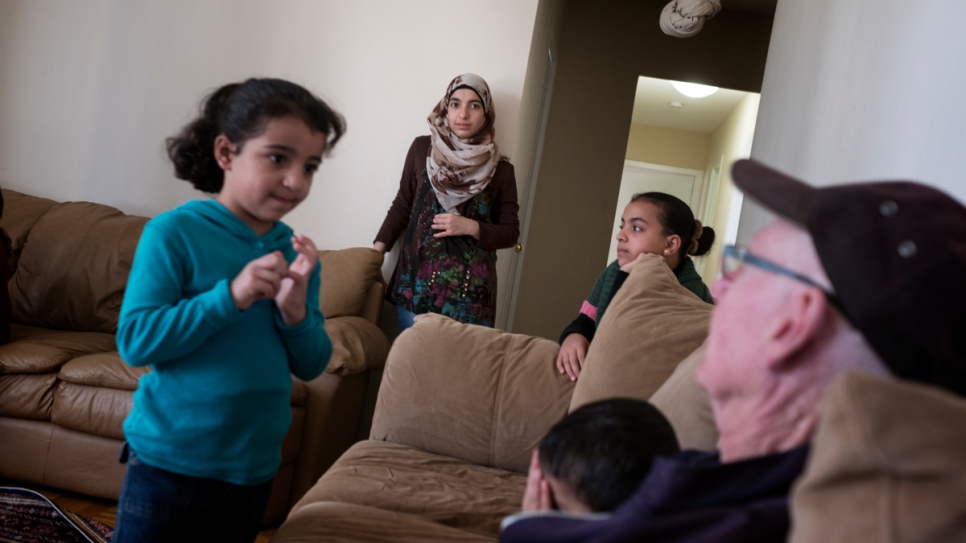 Sponsor Michael Adams (right) visits the Nouman family at their home in Toronto. The Nouman family is among the 13,000 refugees resettled in Canada over the past year.