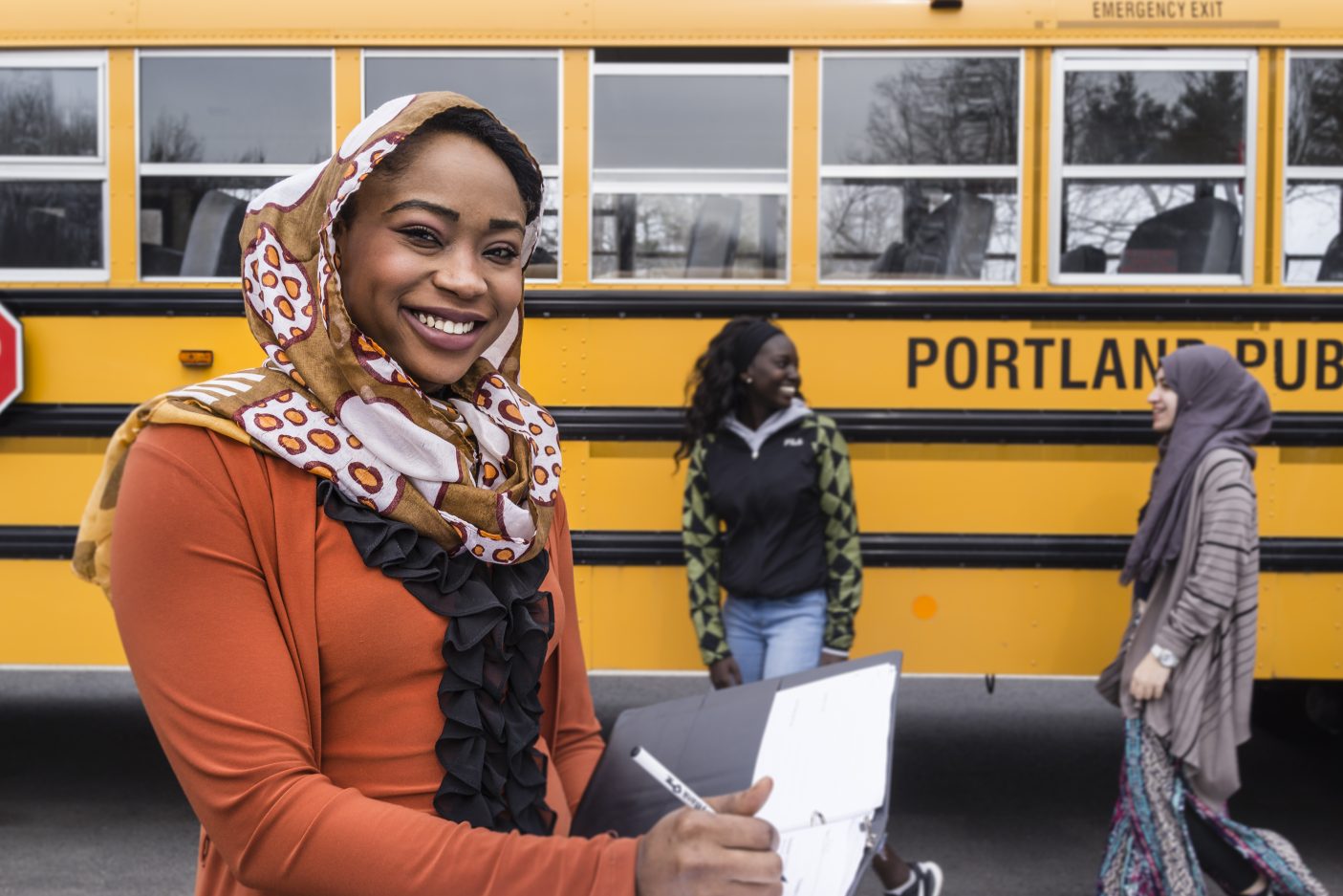 United States. A teacher supervises as her refugee students hang their art work on the wall of their school