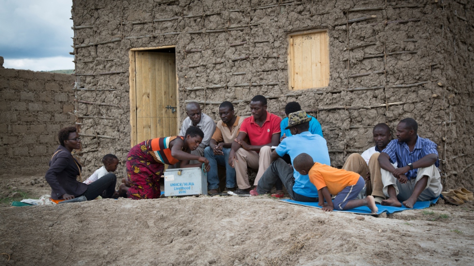 Congolese refugee Janine opens the cash box of the Lake Rwamunga fish farm group in Uganda's Isingiro district to count out savings and grant loans to members. The group meets once a week at Janine's house.