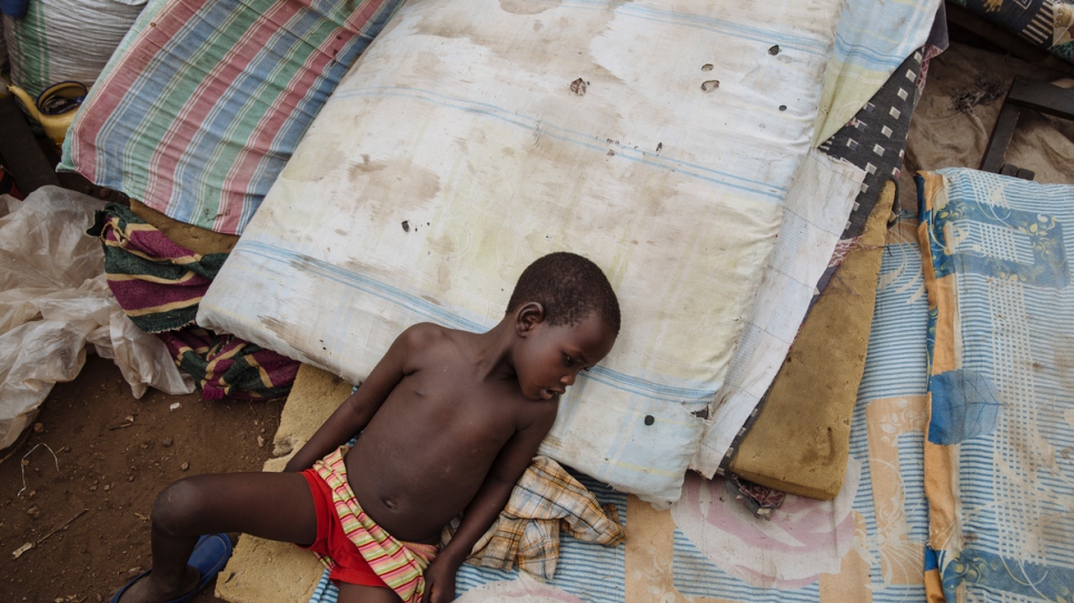 Un réfugié du Soudan du Sud repose sur des matelas placés sur le sol au centre de réception d'Imvepi, district d'Arua, région du Nord, en Ouganda. Les matelas font partie des objets personnels que les réfugiés ont transportés à travers la frontière avec l'Ouganda. 