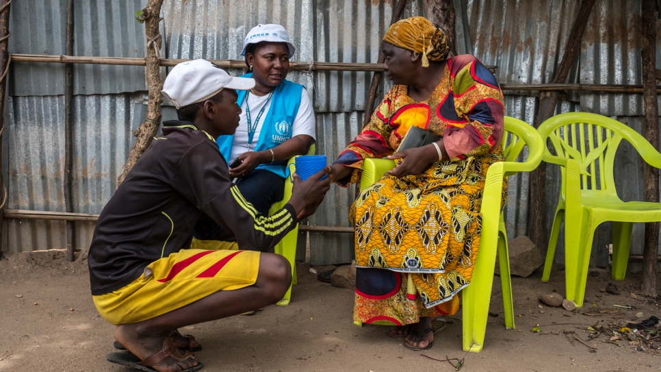 Rehema Kankindi (right) speaks with a UNHCR worker near her home in Uvira. She earns a small income to support her family from her grocery stall.
