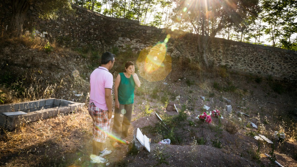 Efi Latsoudi and friend Mohammadhi, an Afghan refugee who now works as an interpreter on Lesvos, talk together at the cemetery.