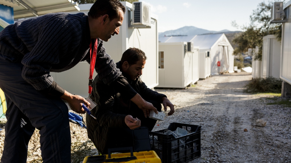 Mohamed (left) and his brother Mofeed, prepare electrical boxes, before wiring them into prefabricated houses at Kara Tepe accommodation facility.