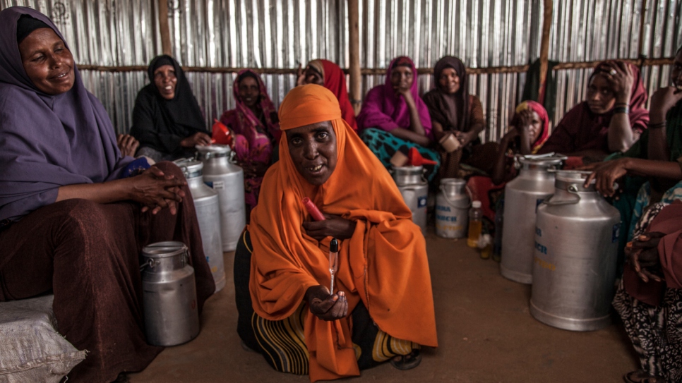 Co-op member Jamila, surrounded by her co-workers, shows off a floating milk thermometer at the Dairy Retail Cooperative at the Melkadida Camp. Together they generate enough income to sustain the business and support their families. "We are used to selling milk. In our culture it is the women who sell milk and we are glad we are able to do the same here."