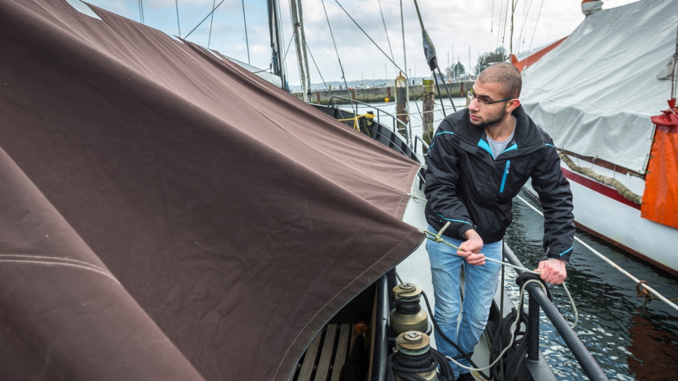 Yousef ties down a boat cover he repaired with his father Mohammed at the Kiel sailmaking company Coastworxx.