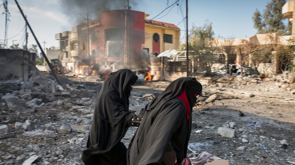 A family flees their destroyed home minutes after a suicide car bomber detonated his vehicle on the street outside in the Al Andalus neighbourhood of Mosul.