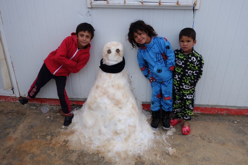 Syrian refugee children pose with a snowman they sculpted at Jordan's Za'atari refugee camp, as the winter storm rages on.