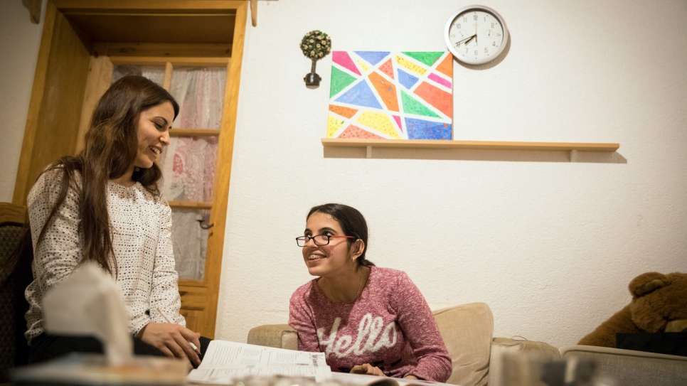 نوجين تساعد شقيقتها الكبرى نسرين، 26 عاماً، في فرضها باللغة الألمانية.