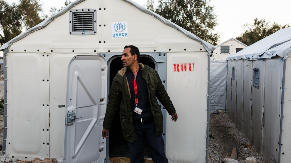 Mohamed attend à l'extérieur d'un logement pour réfugiés au centre d'hébergement de Kara Tepe, où il travaille bénévolement comme électricien avec Mofeed, son frère. 