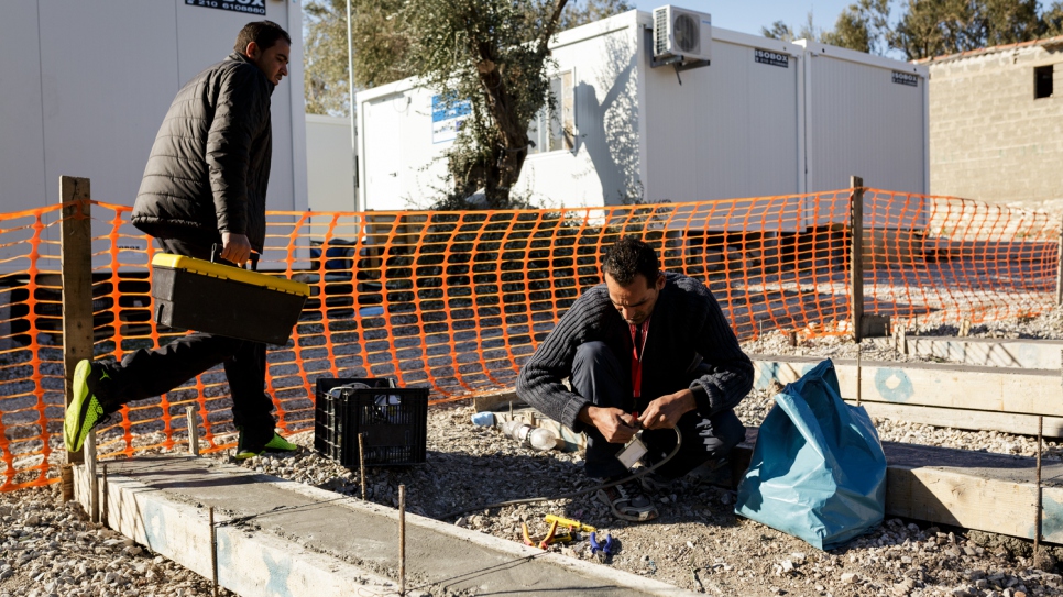 Mohamed (left) and his brother Mofeed, prepare electrical boxes, before wiring them into prefabricated houses at Kara Tepe accommodation facility.