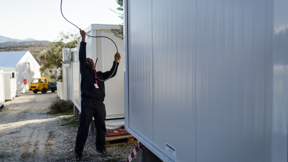 Mohamed installs electric cables at a newly installed prefabricated house, inside the Kara Tepe accommodation facility.
