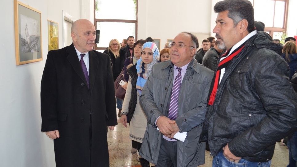 Shergo admires his drawings with Crisis Management Centre director Agron Buxhaku and UNHCR's Mohammad Arif.