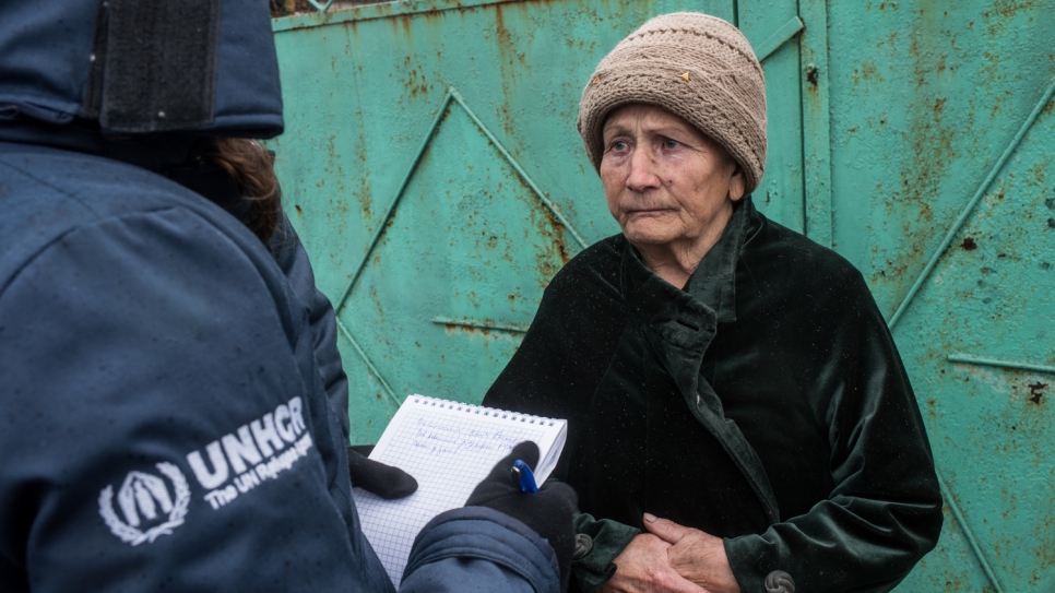 A UNHCR worker writes down 82-year-old Nelya's winter fuel needs in the village of Luhanske, Donetsk.