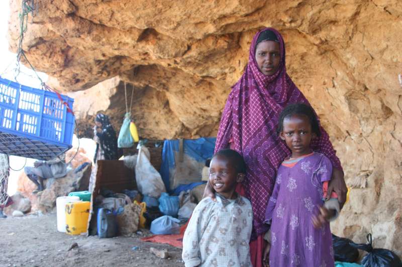 A young mother waits for a boat with her two children. Her husband and two other children are waiting for them in Saudi Arabia.