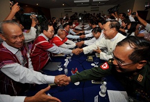 Members of the Karen National Union (left side) and Burmese government (right side) delegations shake hands after peace talks in Rangoon, April 6, 2012.