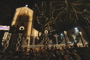 A man walks past a Catholic church decorated with lighting for Christmas in downtown Hanoi, Dec. 22, 2011.